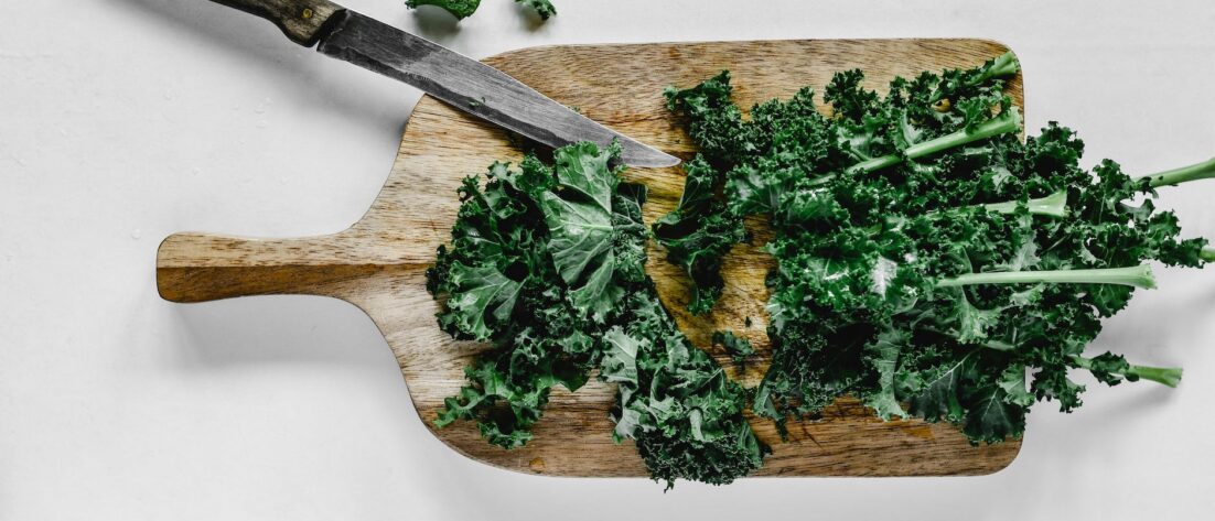 close up shot of chopped kale on a wooden chopping board