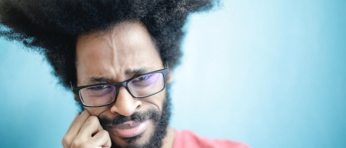 frustrated ethnic man in casual wear on blue background in studio
