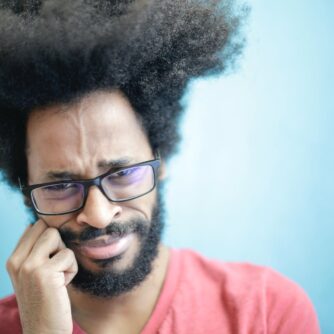 frustrated ethnic man in casual wear on blue background in studio