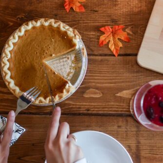 person slicing pumpkin pie