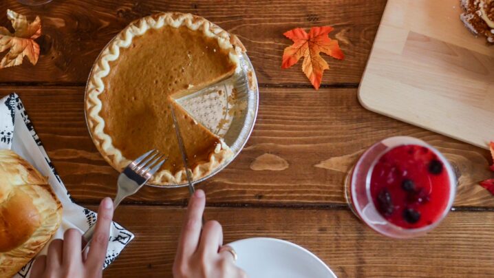 person slicing pumpkin pie