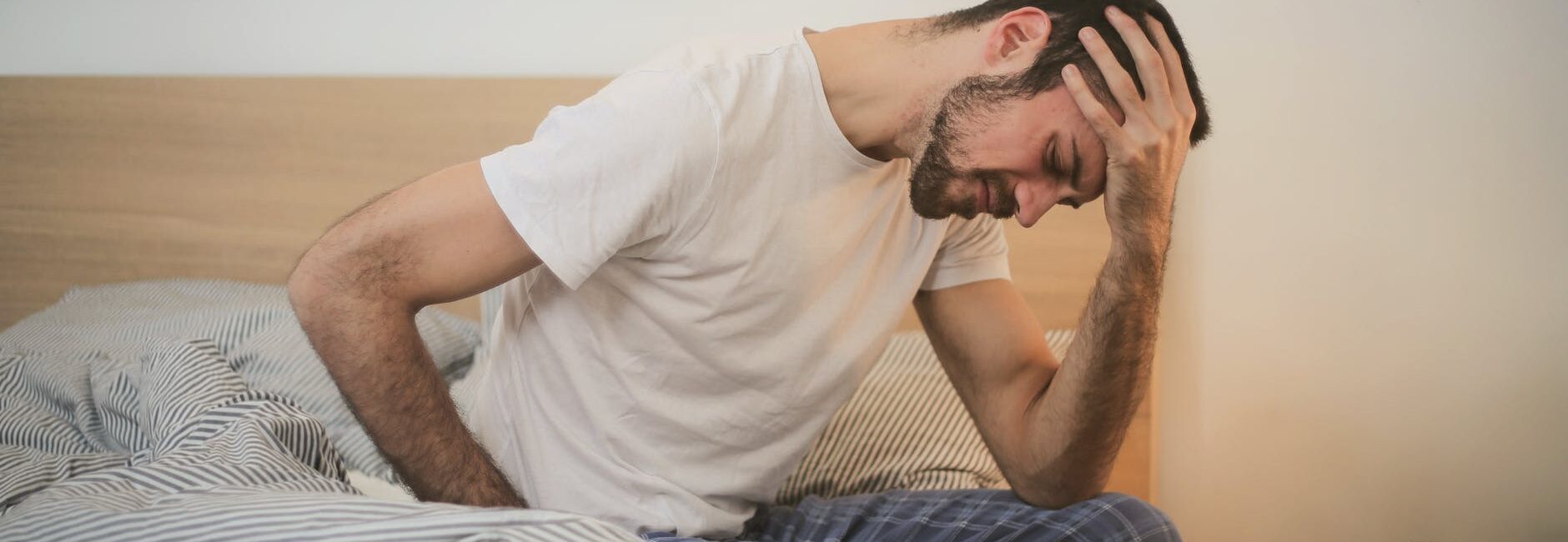 young man in sleepwear suffering from headache in morning