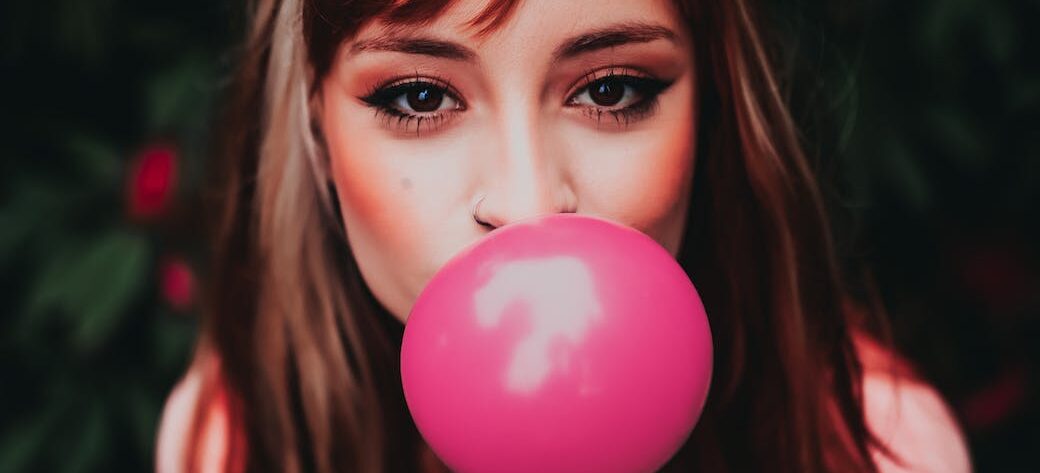 stylish woman blowing bright gum on street
