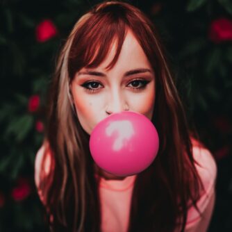 stylish woman blowing bright gum on street