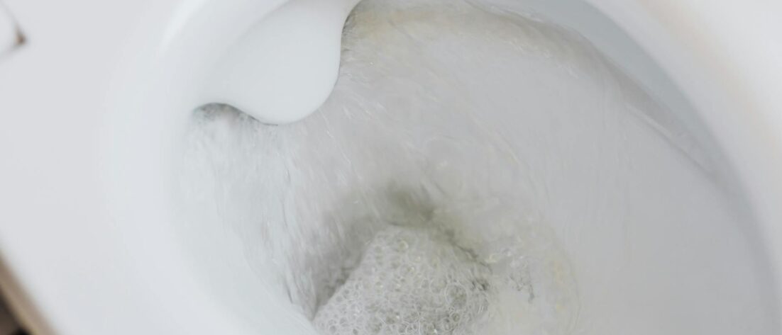 flushing water in white toilet bowl