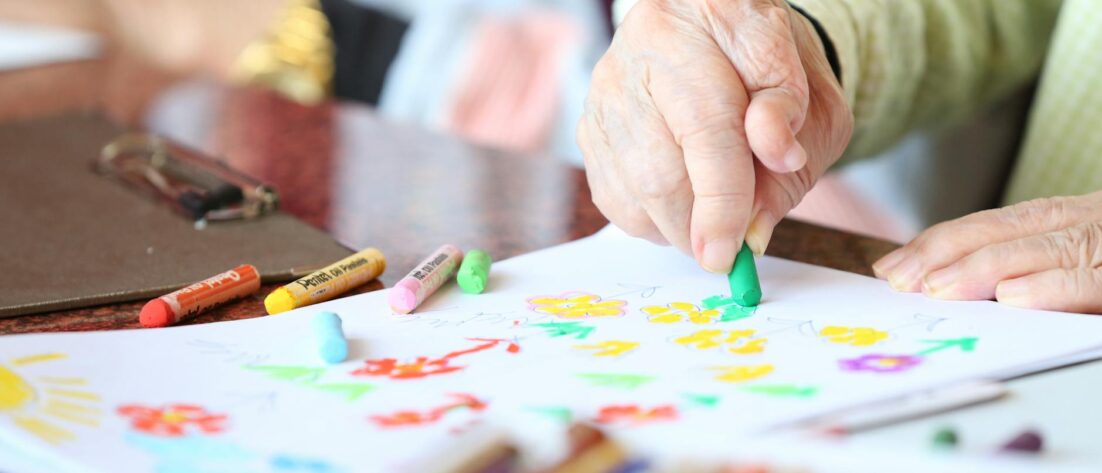 crop senior person drawing with crayons