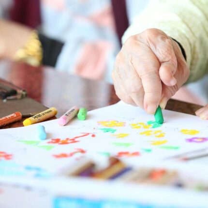 crop senior person drawing with crayons